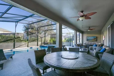 a living room with a table and chairs and a pool at Six Bedroom Disney Home Lanai Screened Pool & Spa villa in Kissimmee
