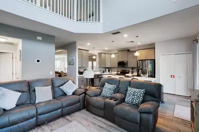 a living room with a leather couch and a kitchen at Six Bedroom Disney Home Lanai Screened Pool & Spa villa in Kissimmee