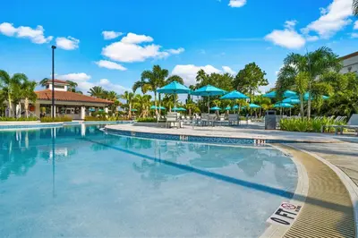 a swimming pool at a resort with blue umbrellas at Vista Cay by CY -Harry Potter 3BR in Orlando