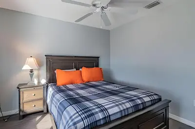 a bedroom with a bed with orange pillows and a ceiling fan at 4Q/2B Seu Refúgio Perto da Disney in Kissimmee