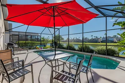 a patio with a table and a red umbrella at 4Q/2B Seu Refúgio Perto da Disney in Kissimmee