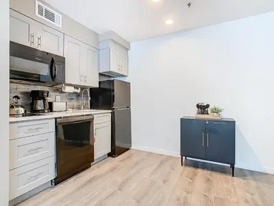a kitchen with stainless steel appliances and white cabinets at Be Our Guest! 1 Bedroom Condo Near Disney Parks! in Orlando