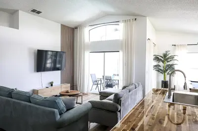 a living room with couches and a tv and a table at Heated pool house with mini golf 10 min to Disney in Orlando