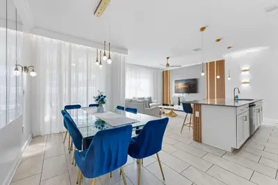 a kitchen and dining room with a glass table and blue chairs at Disney Getaway Prime Location Themed Rooms in Kissimmee