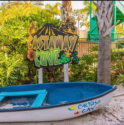 a small boat sitting on the beach with a sign at Paradise island near Disney in Kissimmee