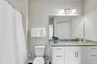 a bathroom with a toilet and a sink and a mirror at Disney World Charm Home 4BR and 3BA! in Kissimmee