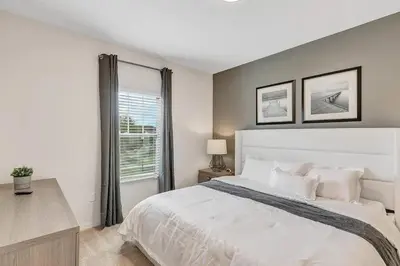 a white bedroom with a large bed and a window at Disney World Charm Home 4BR and 3BA! in Kissimmee