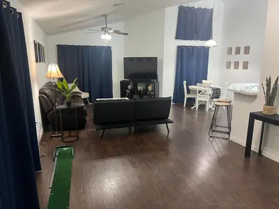 a living room with a couch and a tv and blue curtains at Resort Community 4 Bedroom Family Home, Pool & 15 Min Disney in Kissimmee
