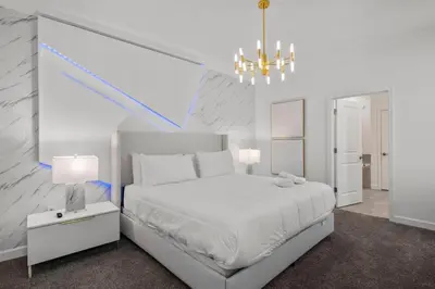 a white bedroom with a large bed and a chandelier at 2912 Storey Lake new game room 24 guests poolspa in Kissimmee