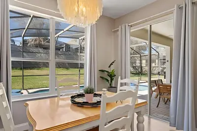 a dining room with a table and chairs and a large window at Casa Luxo 4Q c/ Piscina e Game Room Avengers in Orlando