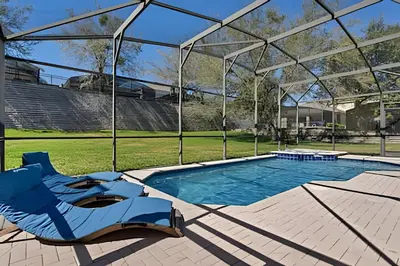 a swimming pool with a blue chair and a pavilion at Casa Luxo 4Q c/ Piscina e Game Room Avengers in Orlando