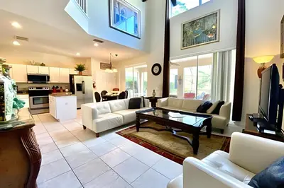 a living room with white furniture and a kitchen at 6Q/5.5B Luxo Piscina Priv. Disney in Kissimmee