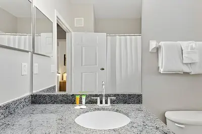 a bathroom with a sink and a toilet and a mirror at Familiar 3 Quartos Perto da Disney! in Orlando