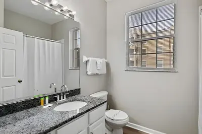 a white bathroom with a toilet and a sink at Familiar 3 Quartos Perto da Disney! in Orlando