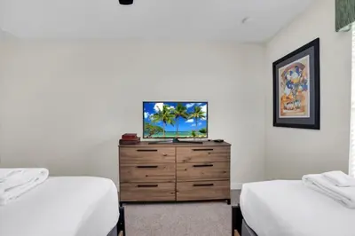 a bedroom with two beds and a dresser with a tv on it at 4804Crusoe townhouse in Kissimmee