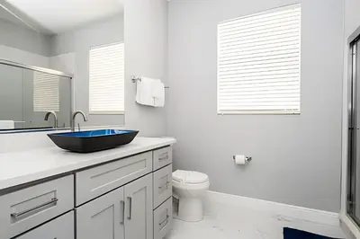 a white bathroom with a sink and a toilet at 6BD/4BA Windsor Hills | Sala de Jogos & Piscina in Orlando