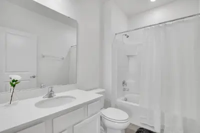 a white bathroom with a toilet and a sink at Amazing 15 Bedroom house at Veranda Palms 2395RAMA villa in Kissimmee