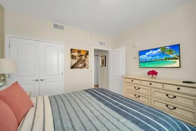 a white bedroom with a bed and a dresser at 4741Clock Unit208 townhouse in Kissimmee