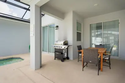 a patio with a table and a grill and a pool at 4Q/3B Luxuosa e Moderna | Piscina Priv. in Kissimmee