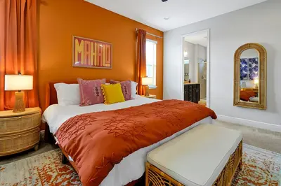 a bedroom with a large bed with orange walls at 5BD Moana-Themed - Movie by the Pool - Near Disney in Orlando