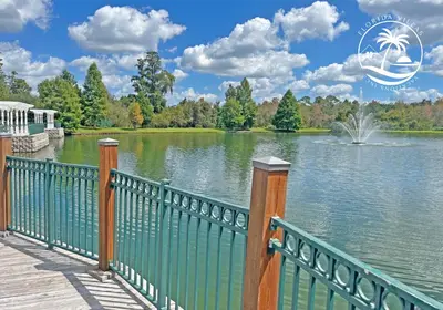a green fence next to a lake with a fountain at Deluxe 4 bedrooms Villa at Seven Dwrafs Resort - Close to Disney in Kissimmee