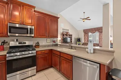 a kitchen with wooden cabinets and stainless steel appliances at Mickeys Sunrise - Phenomenal 7BR Themed Rooms Home Theater Swingset SplashPad Gas BBQ - 2 miles to Disney in Orlando