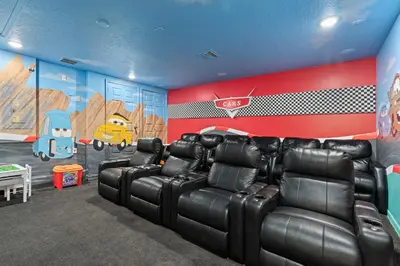 a room with black leather reclining chairs and a wall with a football mural at Mickeys Sunrise - Phenomenal 7BR Themed Rooms Home Theater Swingset SplashPad Gas BBQ - 2 miles to Disney in Orlando