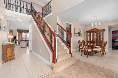 a dining room and kitchen with a staircase in a home at Mickeys Sunrise - Phenomenal 7BR Themed Rooms Home Theater Swingset SplashPad Gas BBQ - 2 miles to Disney in Orlando