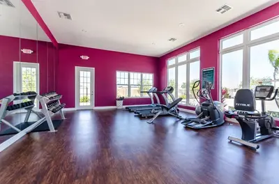 a gym with red walls and tread machines at Casa 3Q West Lucaya c/ Piscina – Perto da Disney in Kissimmee