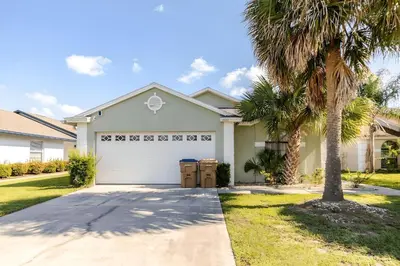 a house with a white garage and palm trees at 3Q/2B Vista para o Lago c/piscina | 10min->Disney in Kissimmee