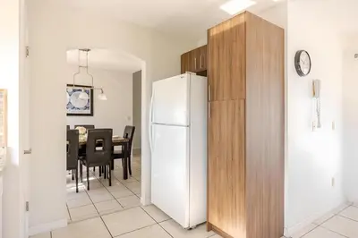 a kitchen with a white refrigerator and a dining room at 3Q/2B Vista para o Lago c/piscina | 10min->Disney in Kissimmee