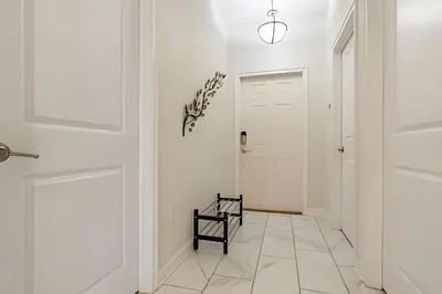 a hallway with a white door and a black chair at Casa 5Q c/ Piscina – 10min da Disney + Resort in Kissimmee