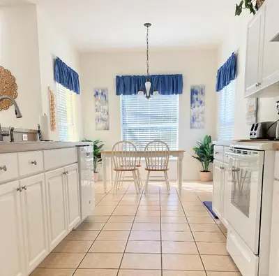 a kitchen with white cabinets and a table and chairs at Grand Cumbrian - Four Bedroom Home in Kissimmee