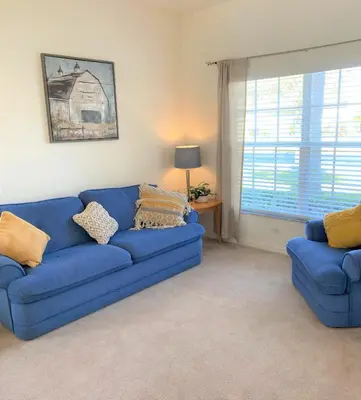 a living room with a blue couch and a window at Grand Cumbrian - Four Bedroom Home in Kissimmee