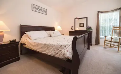 a bedroom with a bed and a mirror and a chair at Cumbrian Retreat in Kissimmee