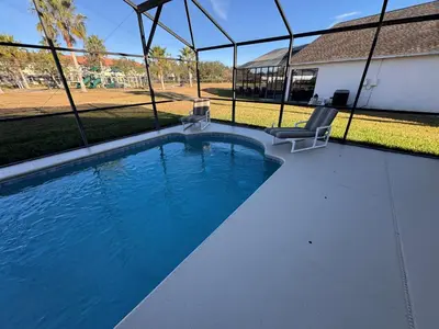a swimming pool with two chairs and a baseball field at Casablanca Villa in Kissimmee