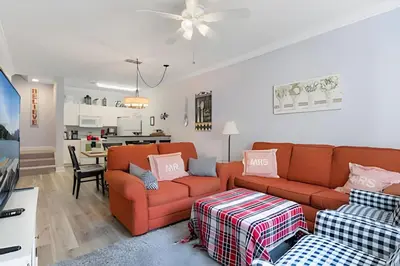 a living room with two orange couches and a kitchen at Casa Moderna 3Q – Perto da Disney in Kissimmee