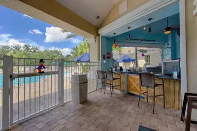 a balcony with a kitchen and a bar with chairs at Windsor Palms Oasis Harry Potter Mickey Pool Spa in Kissimmee