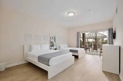 a white bedroom with two beds and a balcony at New in the market apt with big terrace! in Orlando