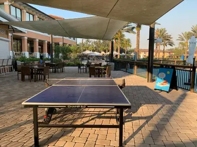 a ping pong table on a patio with tables and chairs at Four Bedroom Townhouse in Regal Oaks at Old Town in Orlando