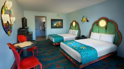 a hotel room with two beds and a table and a chair at Disney's Art Of Animation Resort in Orlando