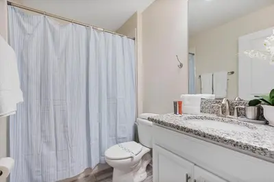 a white bathroom with a toilet and a sink at Amazing 5Bdrms At Storey Lake in Kissimmee