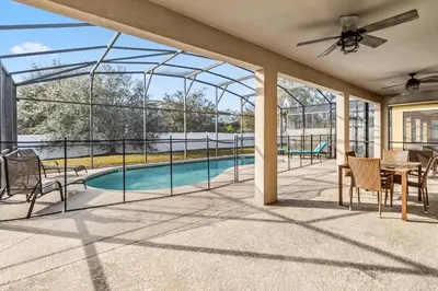 a screened porch with a table and chairs and a pool at 765 Beautiful Vacation Home With Private Pool, And Much More!! in Kissimmee