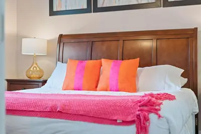 a bedroom with a bed with pink and orange pillows at Luxury Design with close proximity to DISNEY in Kissimmee