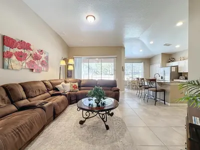 a living room with a brown couch and a table at Tranquility Palms in a Resort- Steps to Disney in Kissimmee