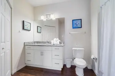 a white bathroom with a toilet and a sink at Casa 4Q c/ Clubhouse – 10 Min da Disney in Kissimmee