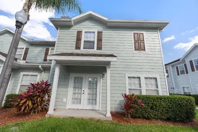 a white house with a palm tree in front of it at Casa 4Q c/ Clubhouse – 10 Min da Disney in Kissimmee