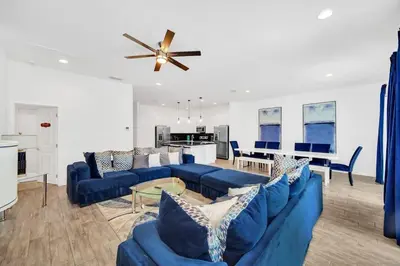 a living room with blue couches and a ceiling fan at EPIC 12 Bedroom Home with Private Pool in Kissimmee