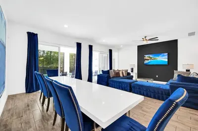 a dining room with a white table and blue chairs at EPIC 12 Bedroom Home with Private Pool in Kissimmee