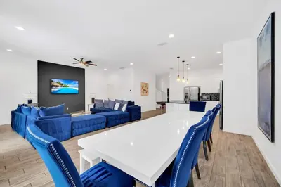 a dining room with a white table and blue chairs at EPIC 12 Bedroom Home with Private Pool in Kissimmee